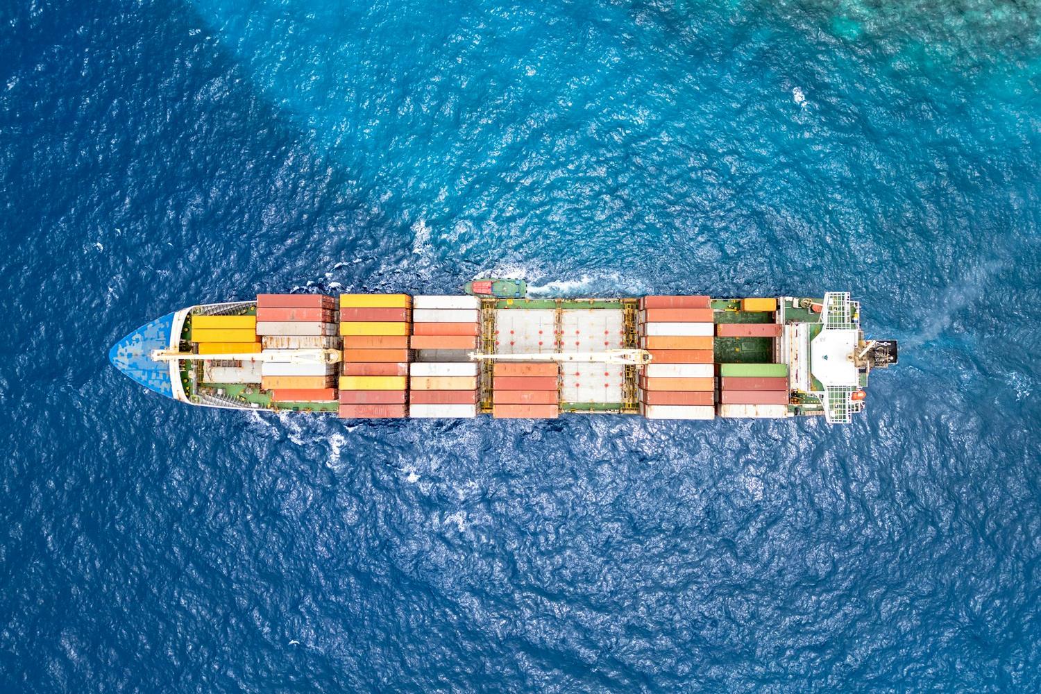 Container ship sailing in open sea, seen from above.